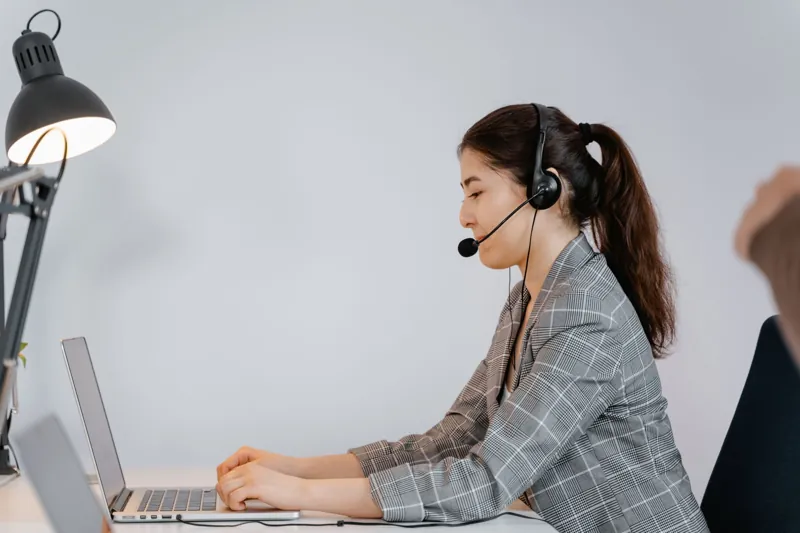 Support agent with a headset working on a laptop